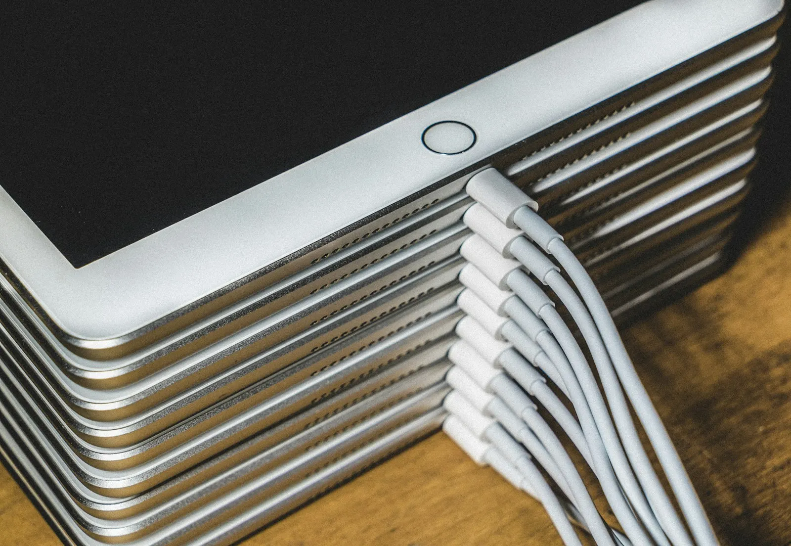 A stack of iPads charging with a cable plugged into each one