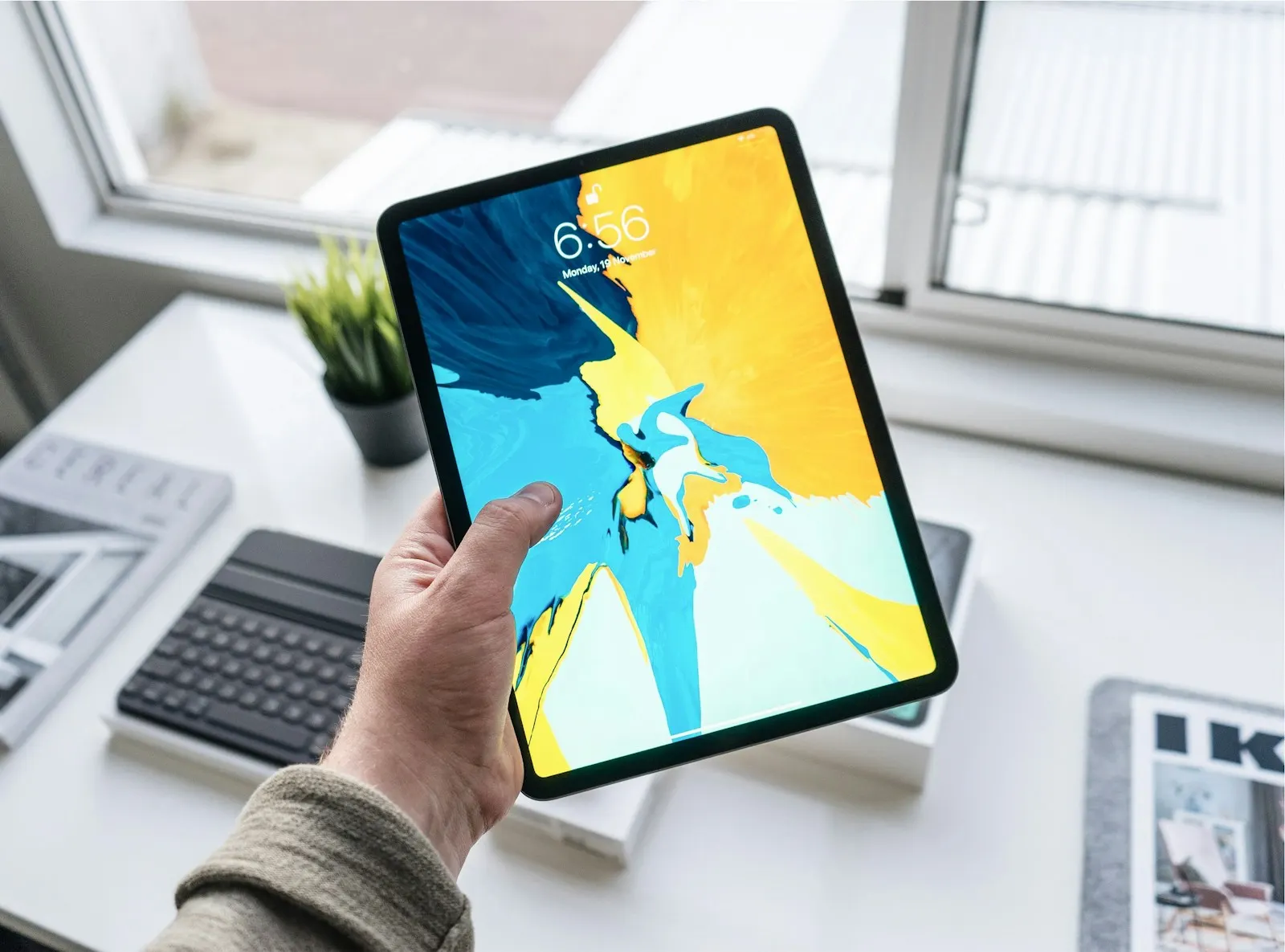 A person holding an iPad Pro with the lock screen showing