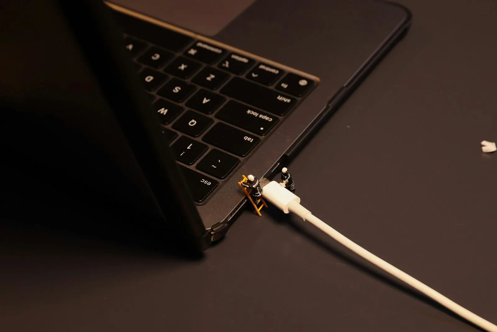 A charging cable plugged into the side port of a laptop