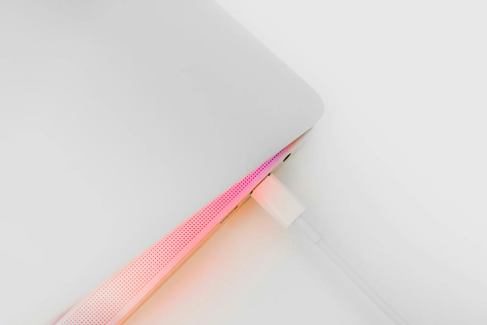 A MagSafe connector glowing while attached to a MacBook