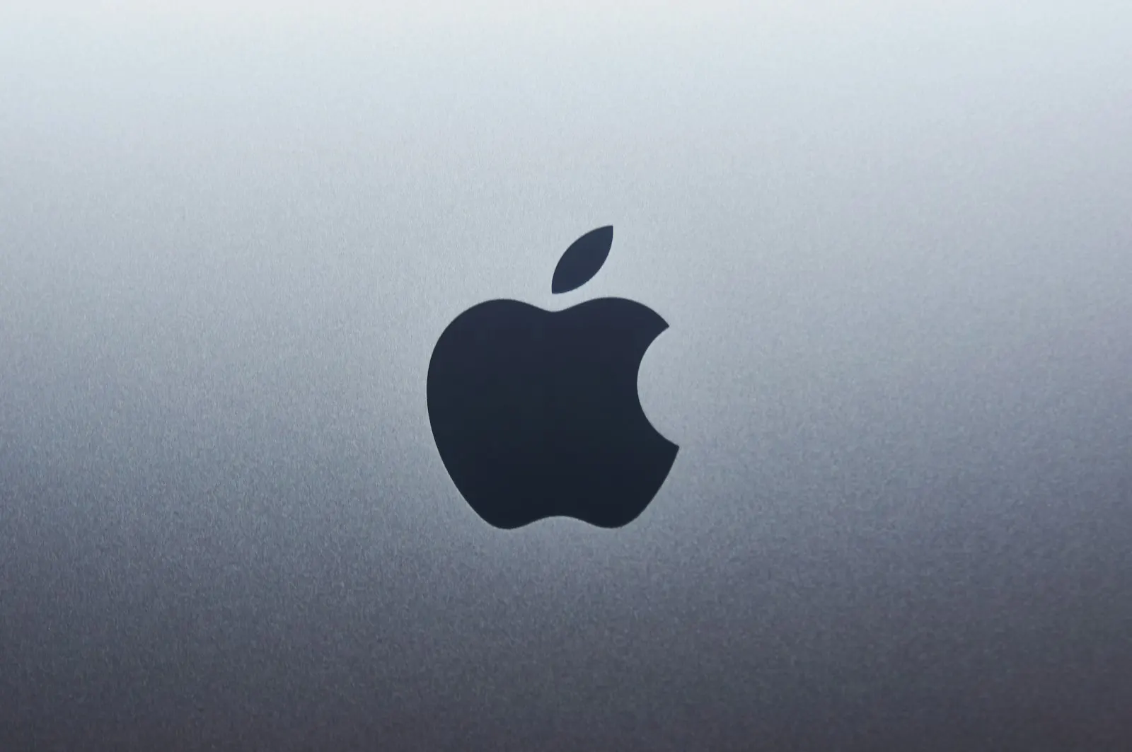 The Apple logo on the lid of a space gray MacBook
