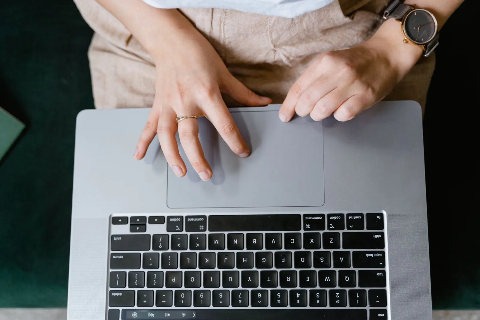 A person resting a hand on a MacBook trackpad, seen from above
