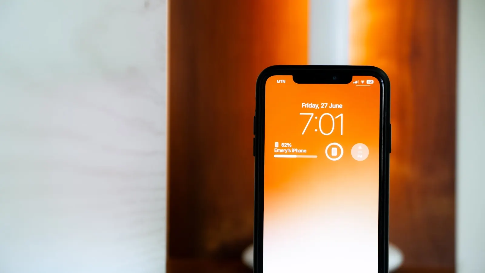 An iPhone lock screen glowing orange on a warm lit table