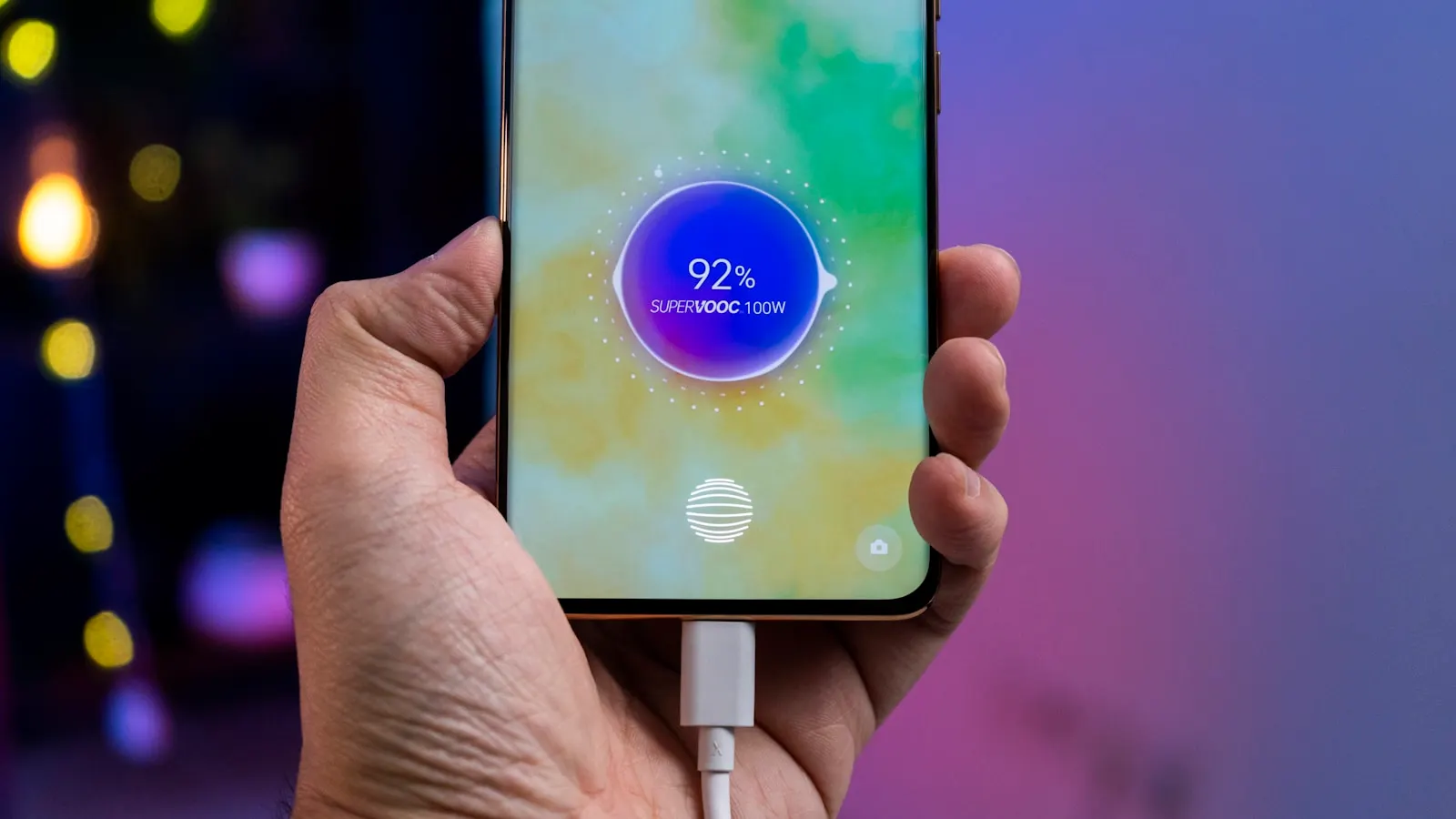 A hand holding a phone showing a 92 percent charging screen with a cable attached