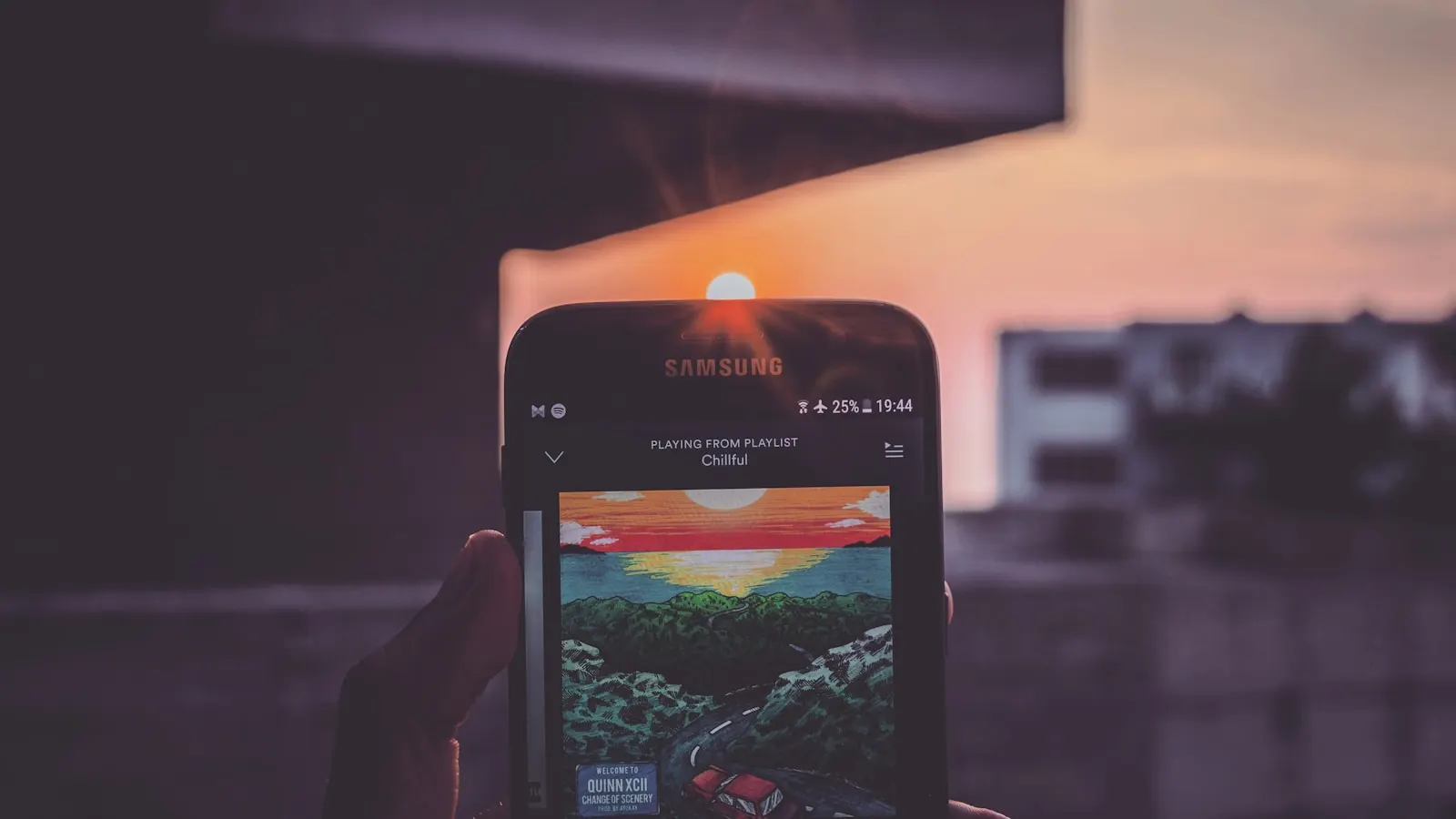 A person holding a Samsung phone up toward the bright sun