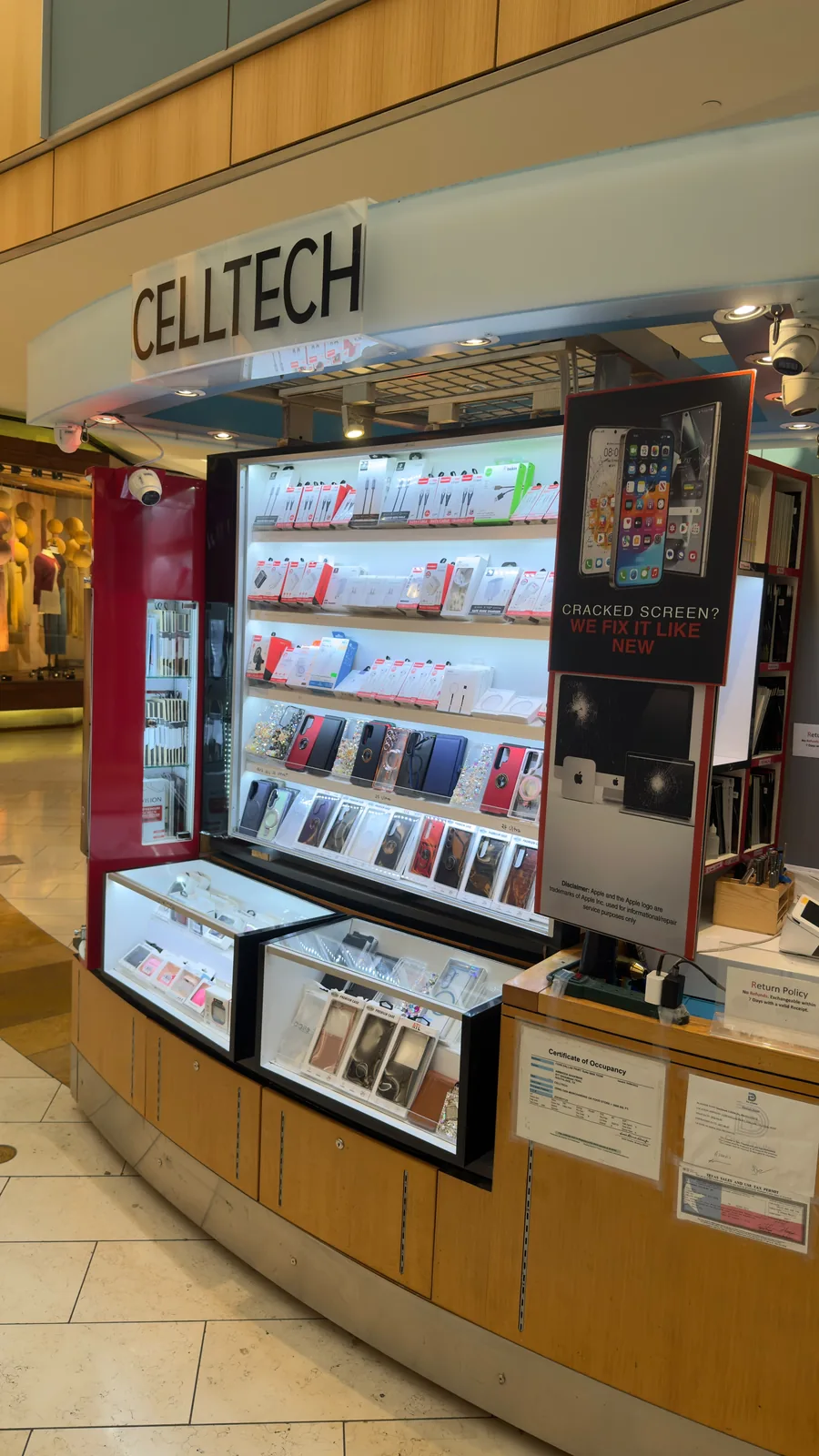 The iPhone repair counter at the CELLTECH kiosk in Galleria Dallas, next to a “Cracked screen? We fix it like new” board