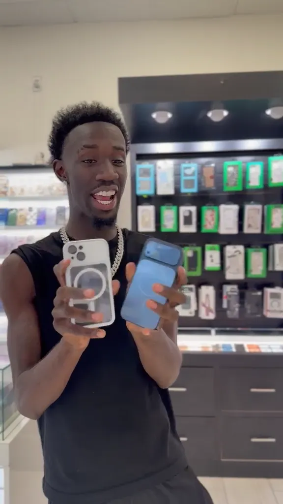 A CELLTECH customer holding up his repaired iPhone at the store counter