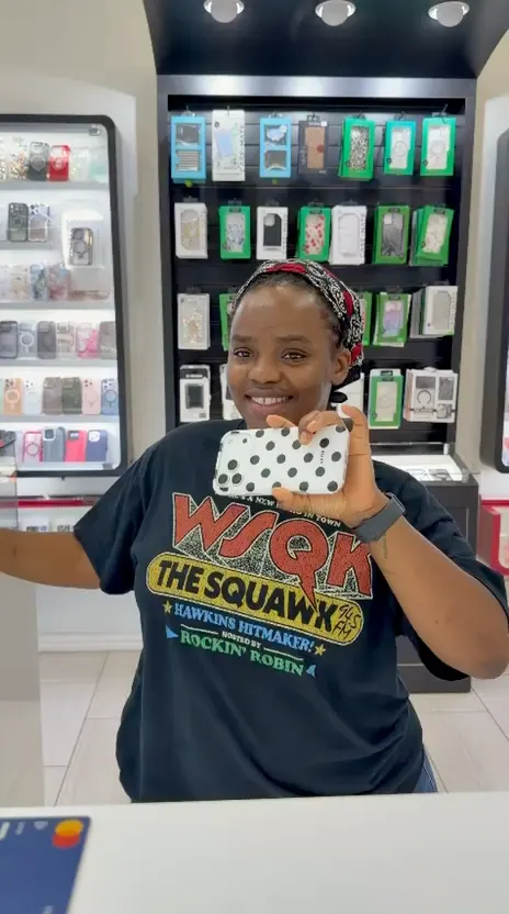 A CELLTECH customer holding up her phone in a polka dot case at The Parks Mall store