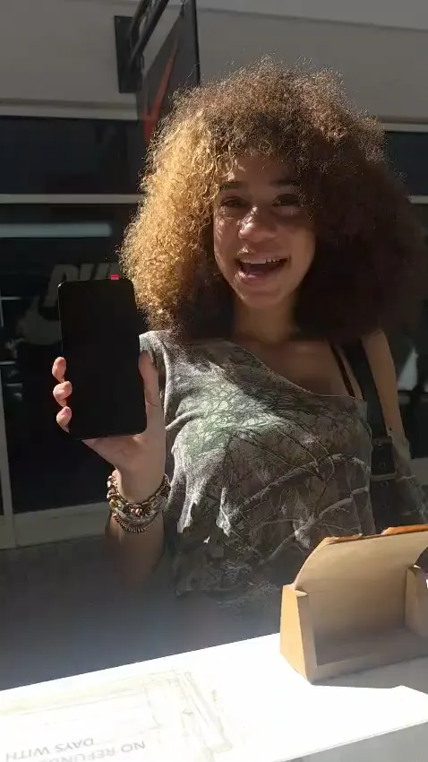 A CELLTECH customer holding up her repaired phone at the Grand Prairie outlet counter