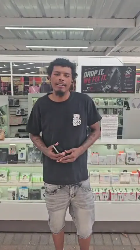 A CELLTECH customer holding his phone in front of the store’s accessories wall