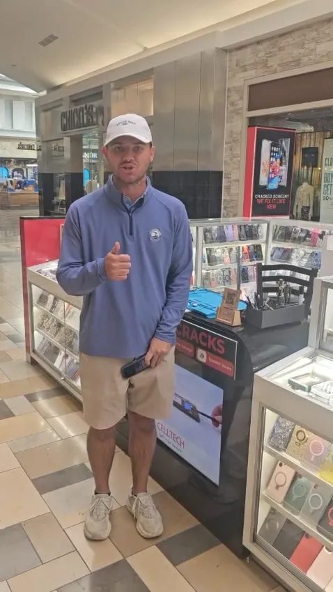 A CELLTECH customer standing beside the store’s mall kiosk, giving a thumbs up