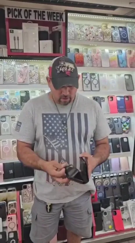 A CELLTECH customer holding his phone in front of a wall of cases