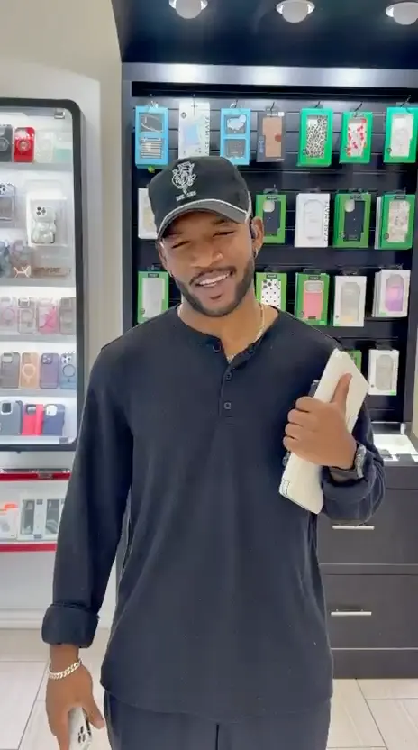 A CELLTECH customer in a cap smiling at the counter of The Parks Mall store