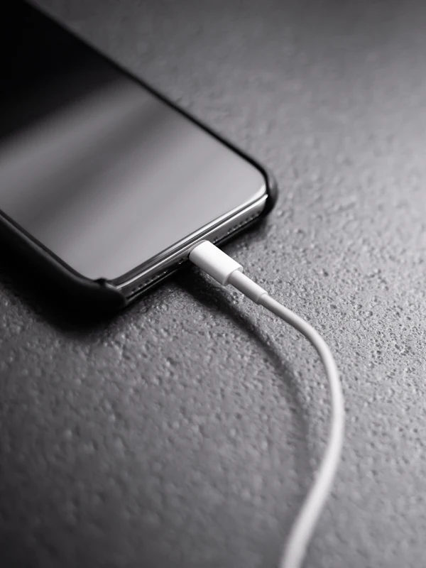 A charging cable plugged into the port at the bottom of an iPhone