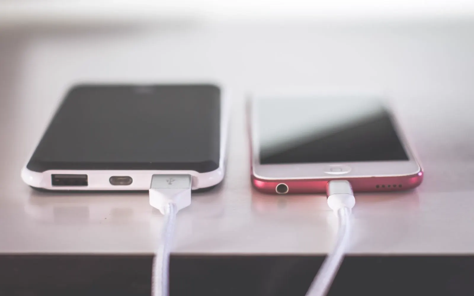 Two smartphones charging side by side on a desk