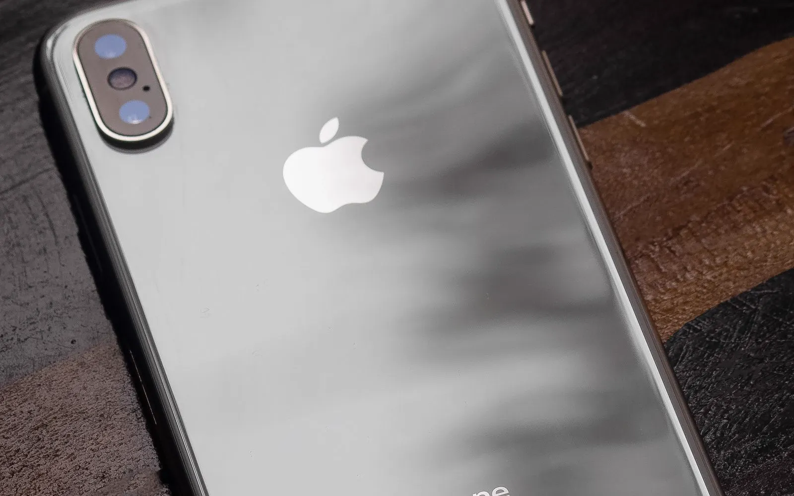 The rear of an iPhone lying face down on a dark wooden table