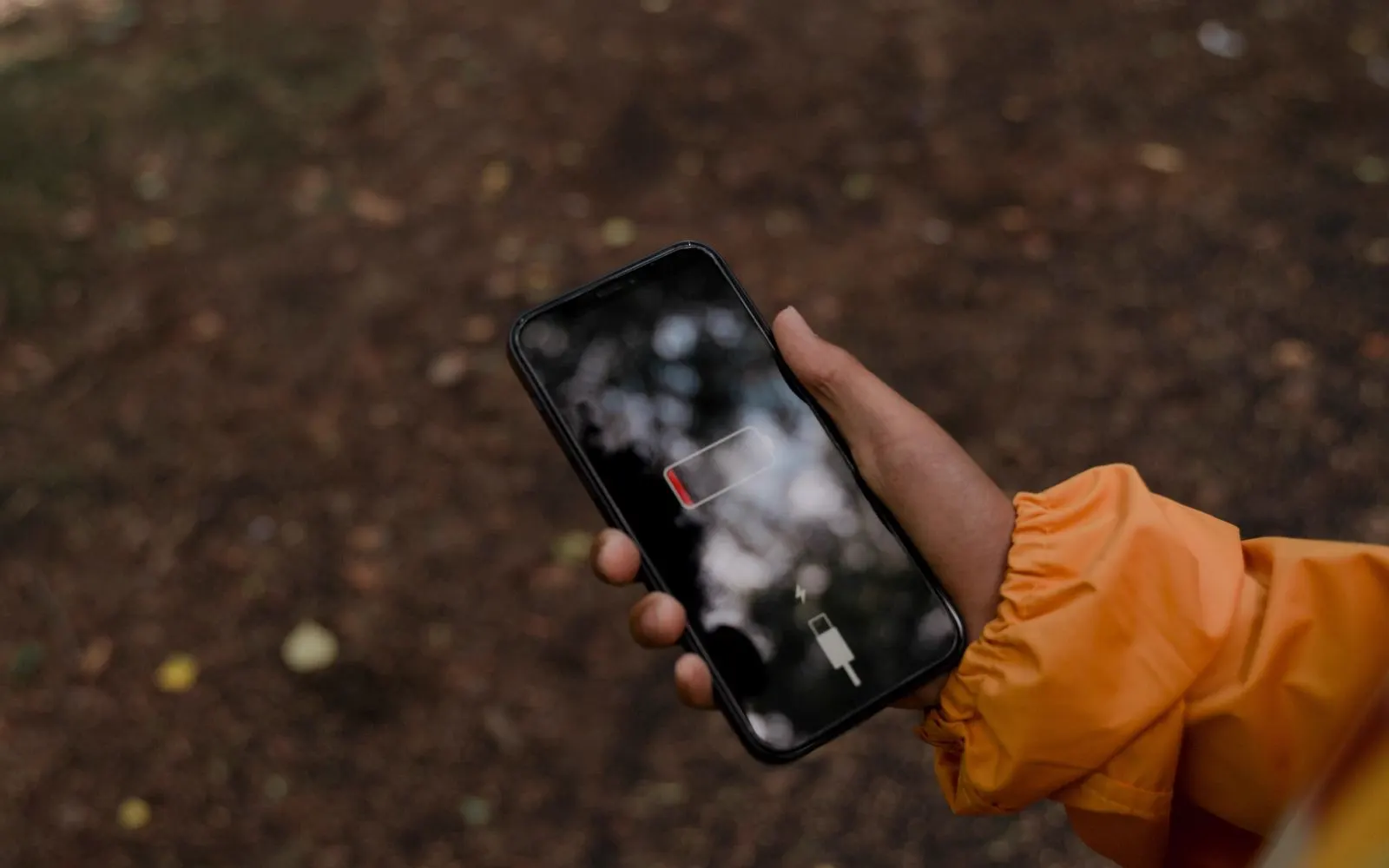A hand holding a smartphone showing a nearly empty battery