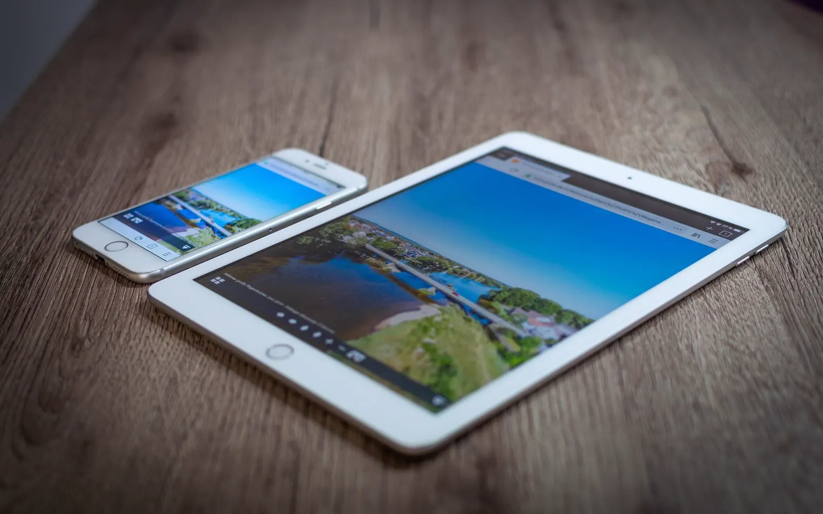 An iPad and an iPhone side by side on a wooden table
