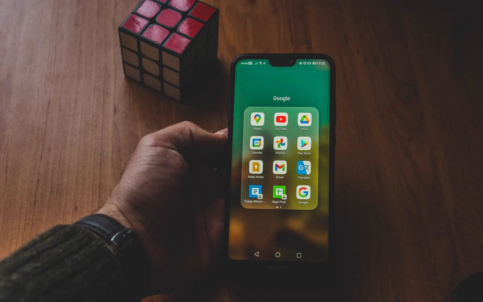 A hand holding an Android phone showing its apps