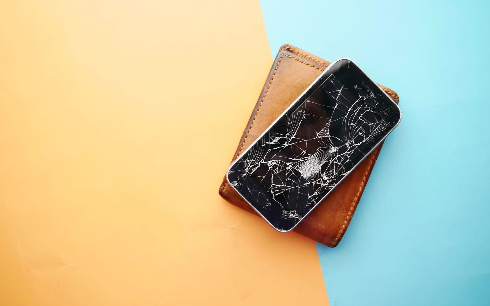 A broken smartphone resting on a wallet