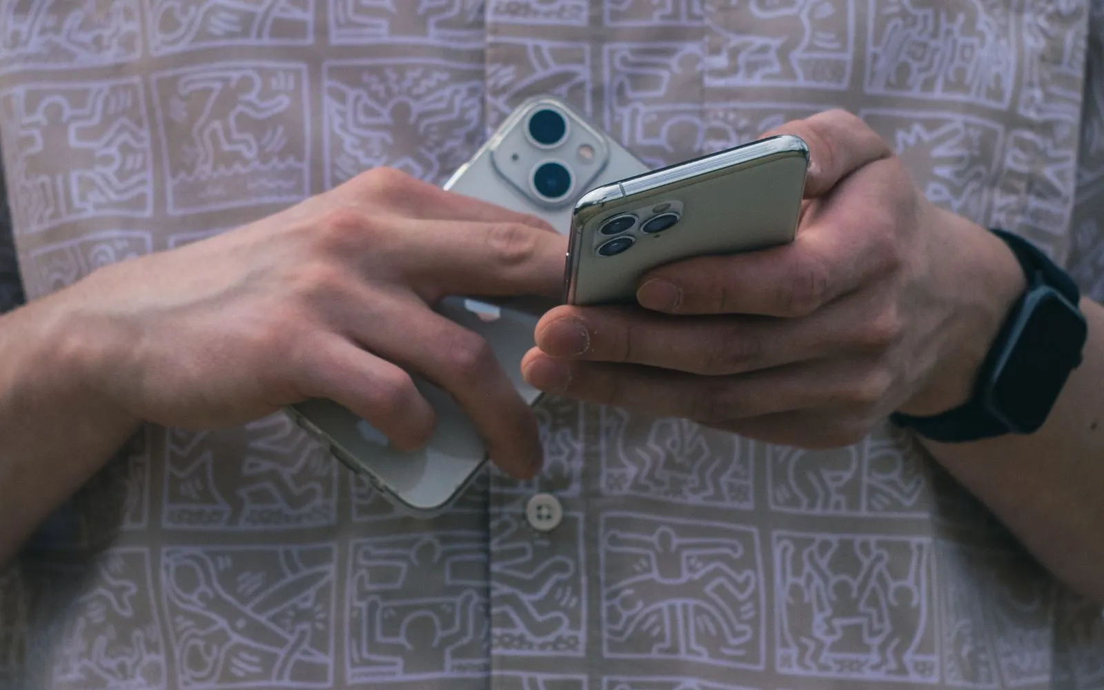 Two hands holding a standard dual camera iPhone beside a triple camera iPhone Pro