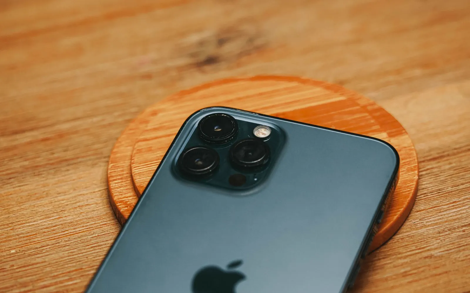 A modern smartphone camera module resting on a wooden surface