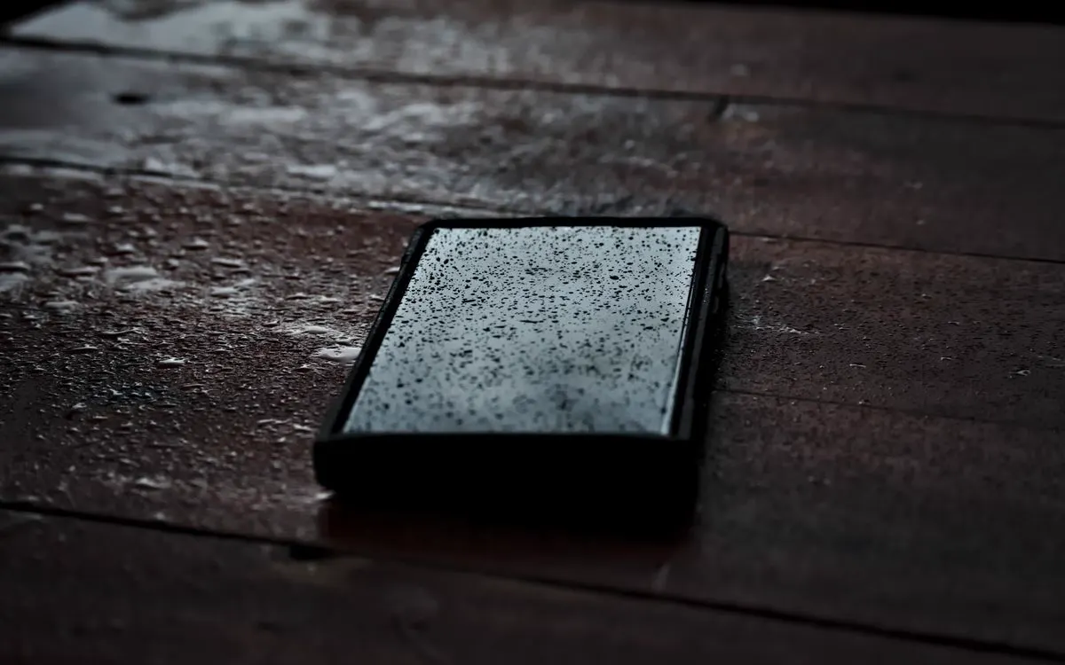 A tablet lying face up on rain-soaked wooden boards