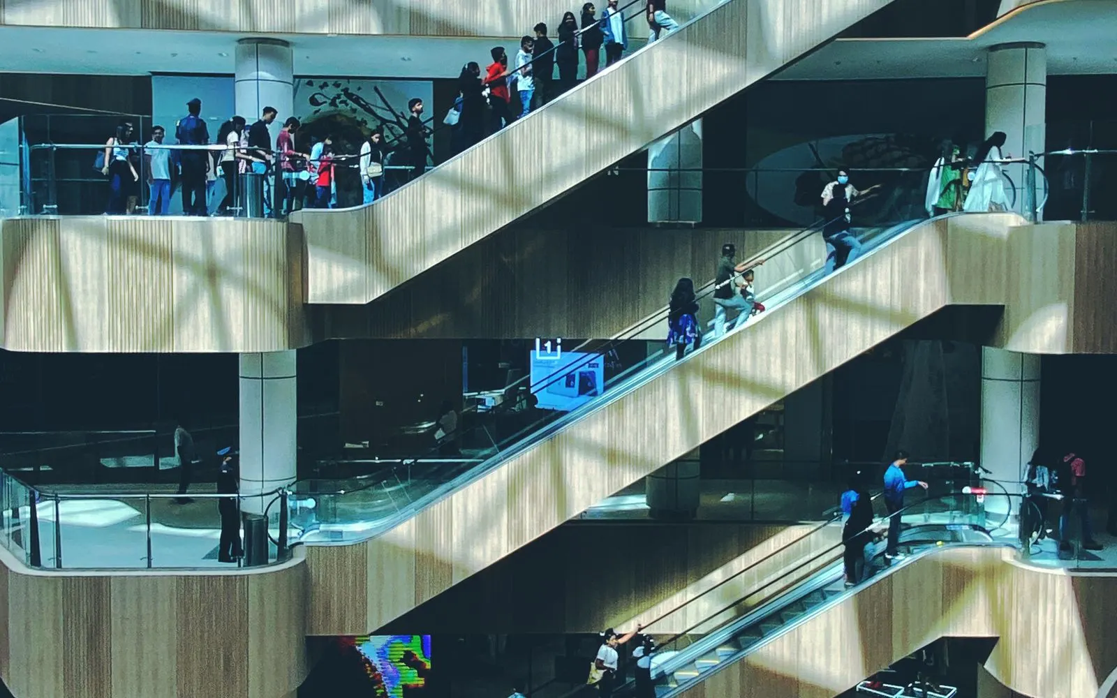 Shoppers riding the escalators between floors of a shopping mall