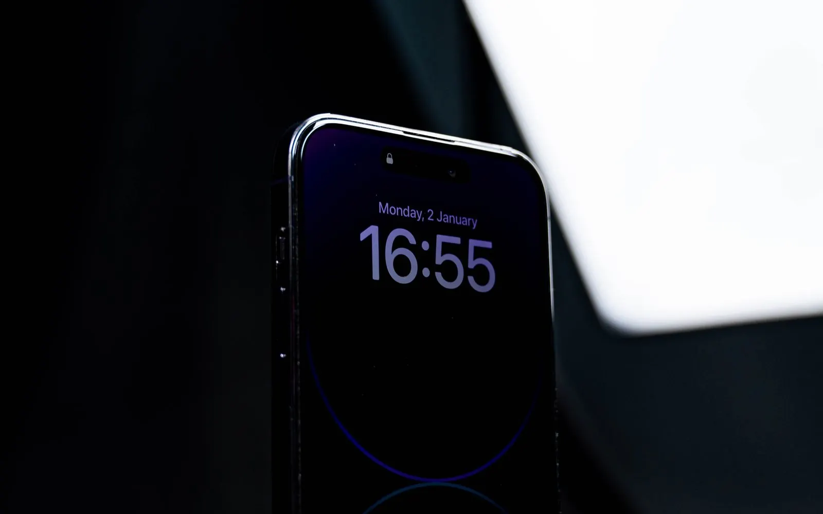 The top of an iPhone lock screen in the dark, where the TrueDepth camera sits
