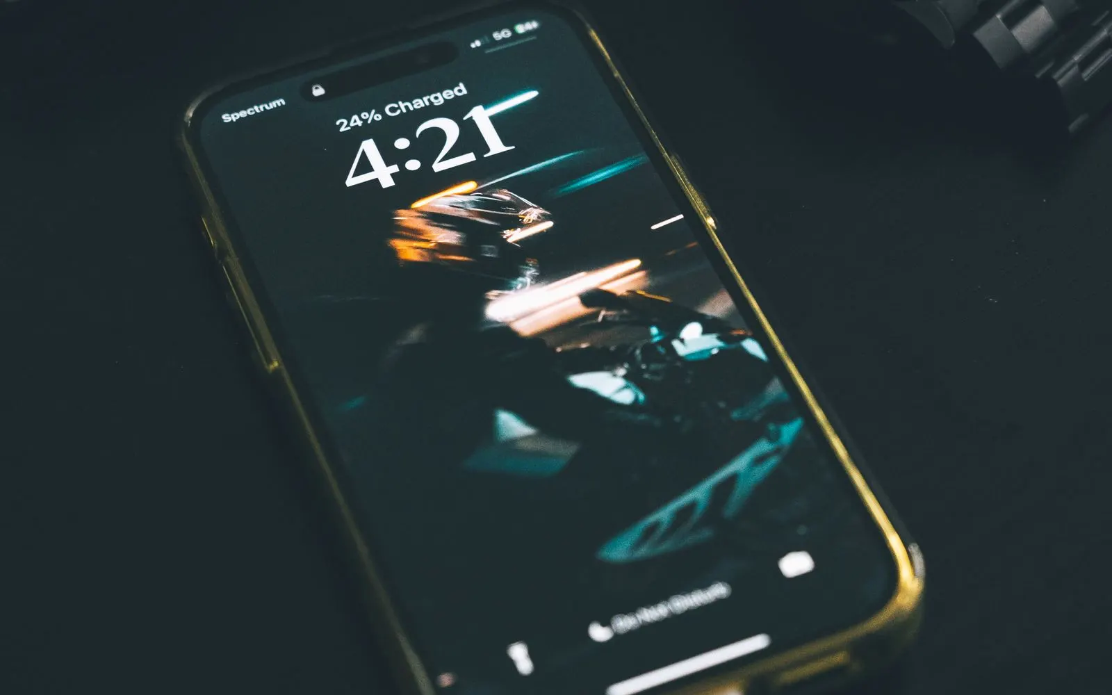 An iPhone lock screen reading 24% Charged, lying on a dark table