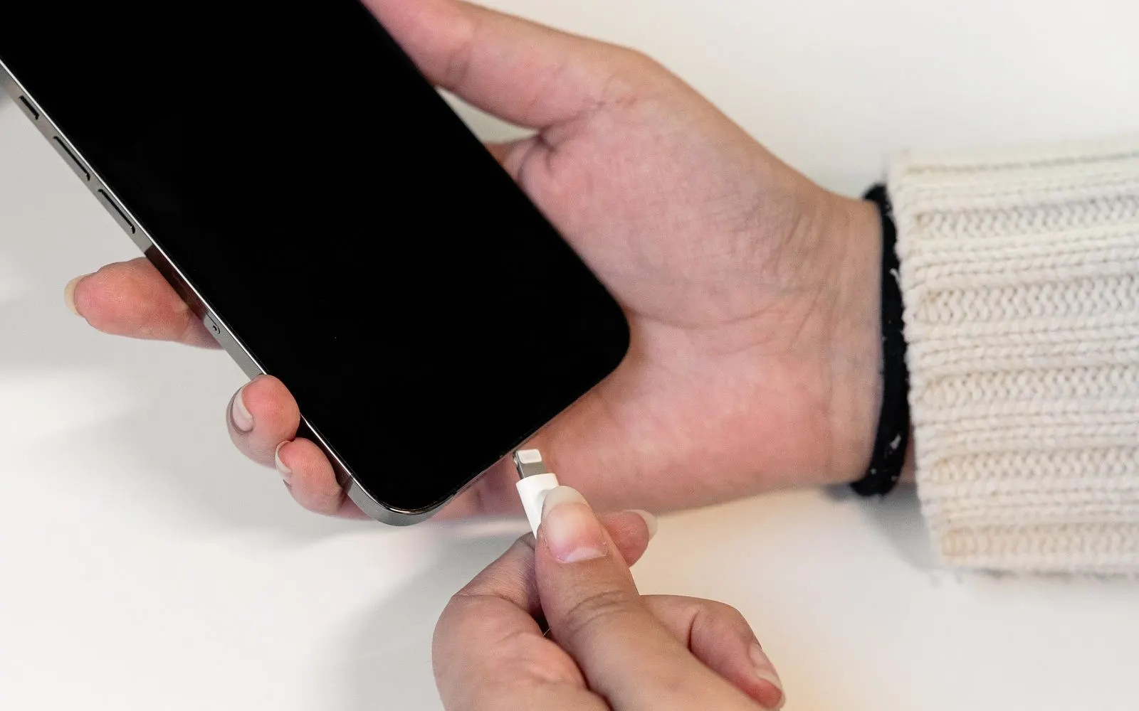A charging cable being plugged into the port at the bottom of an iPhone