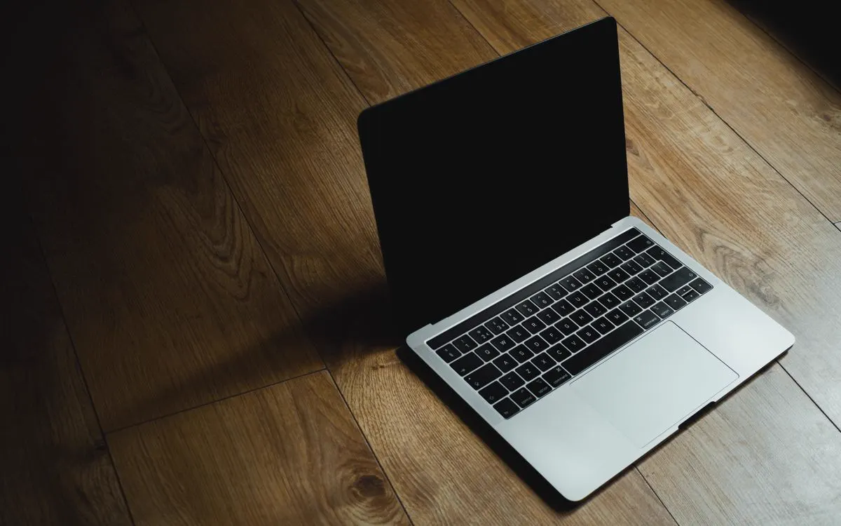 An open MacBook Pro resting on a wooden floor