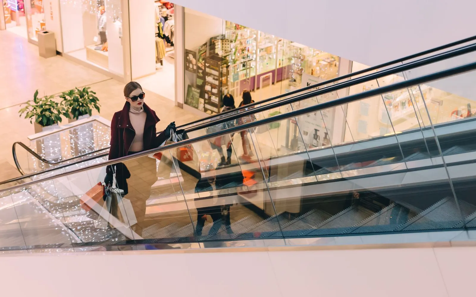 A shopper riding an escalator up to the upper level of a shopping mall