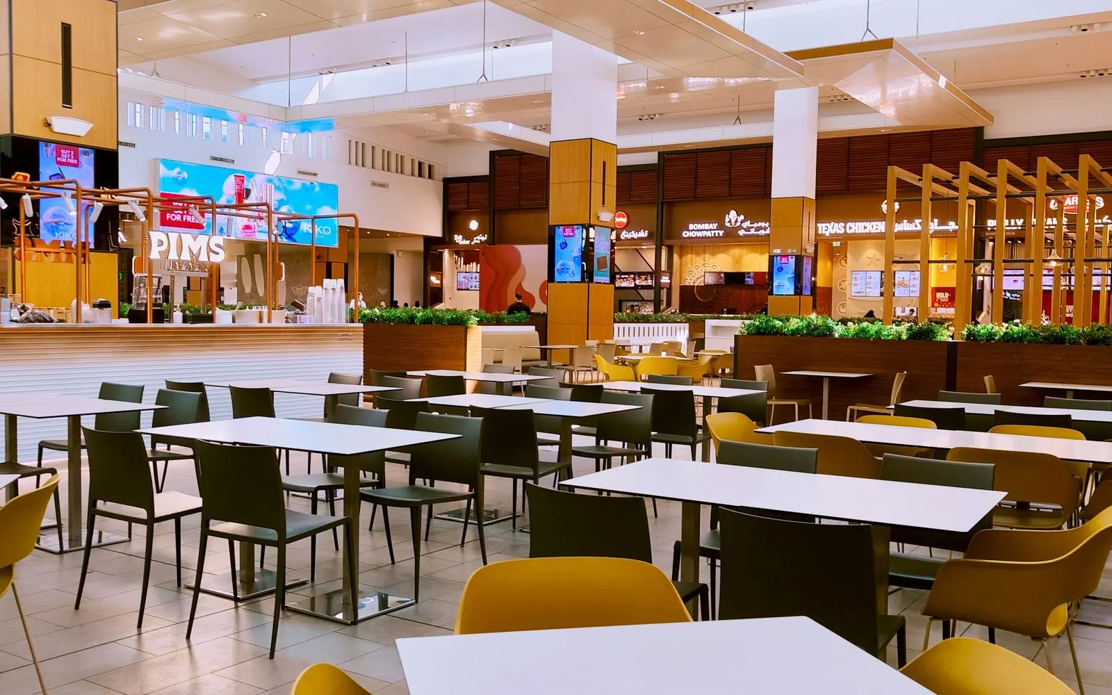 Tables and chairs in a bright shopping mall food court