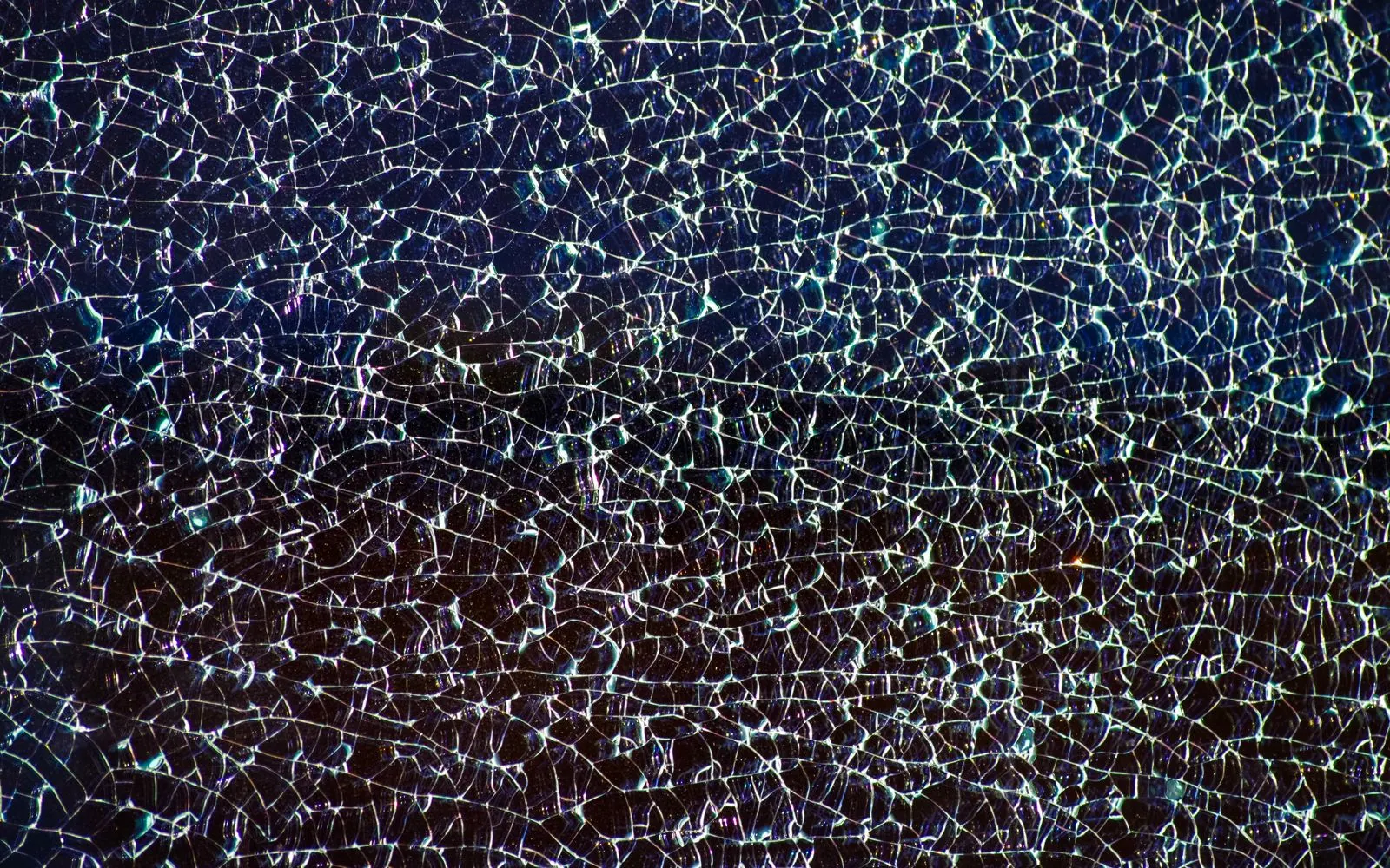 Close-up of dark screen glass crazed with a fine web of cracks from edge to edge