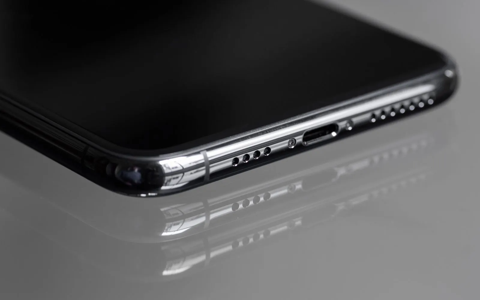 The bottom edge of a black iPhone, its Lightning port and speaker grilles in focus
