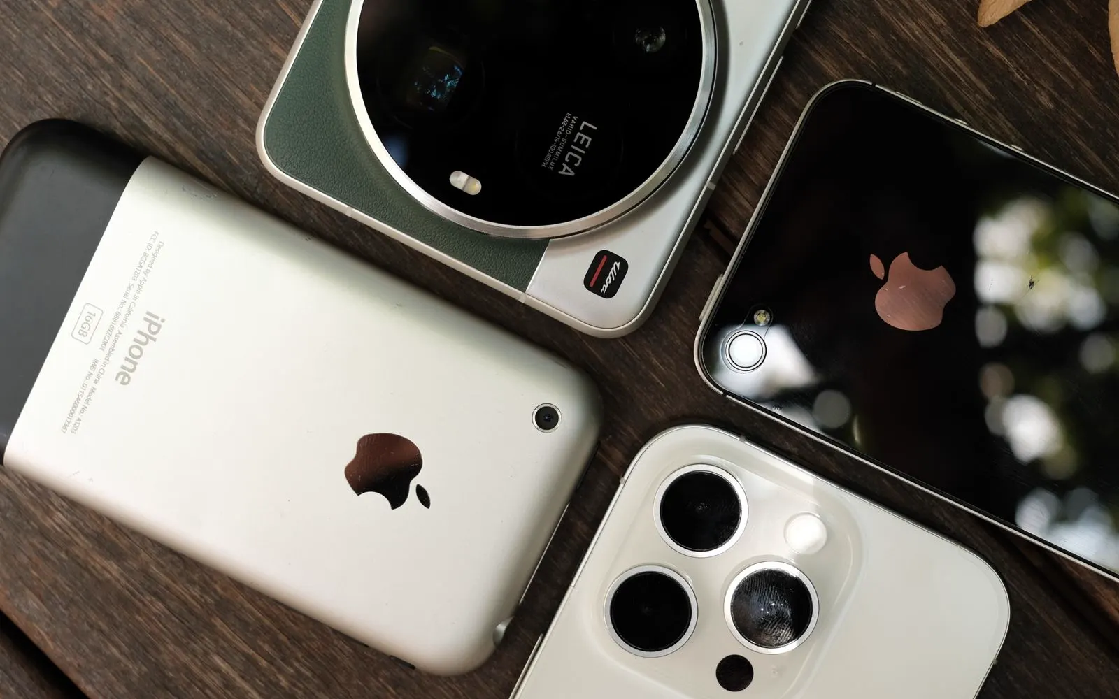 Several smartphone models laid out side by side on a wooden table