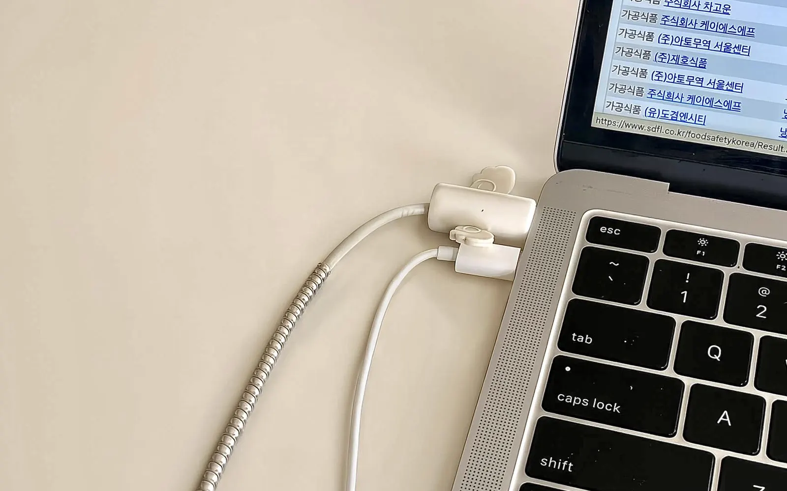 An overhead view of a laptop on a desk with its charging cables connected