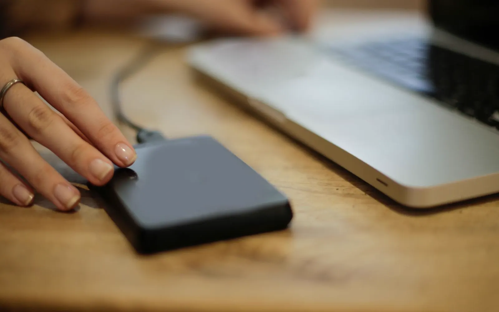 An external drive being connected to a laptop on a desk