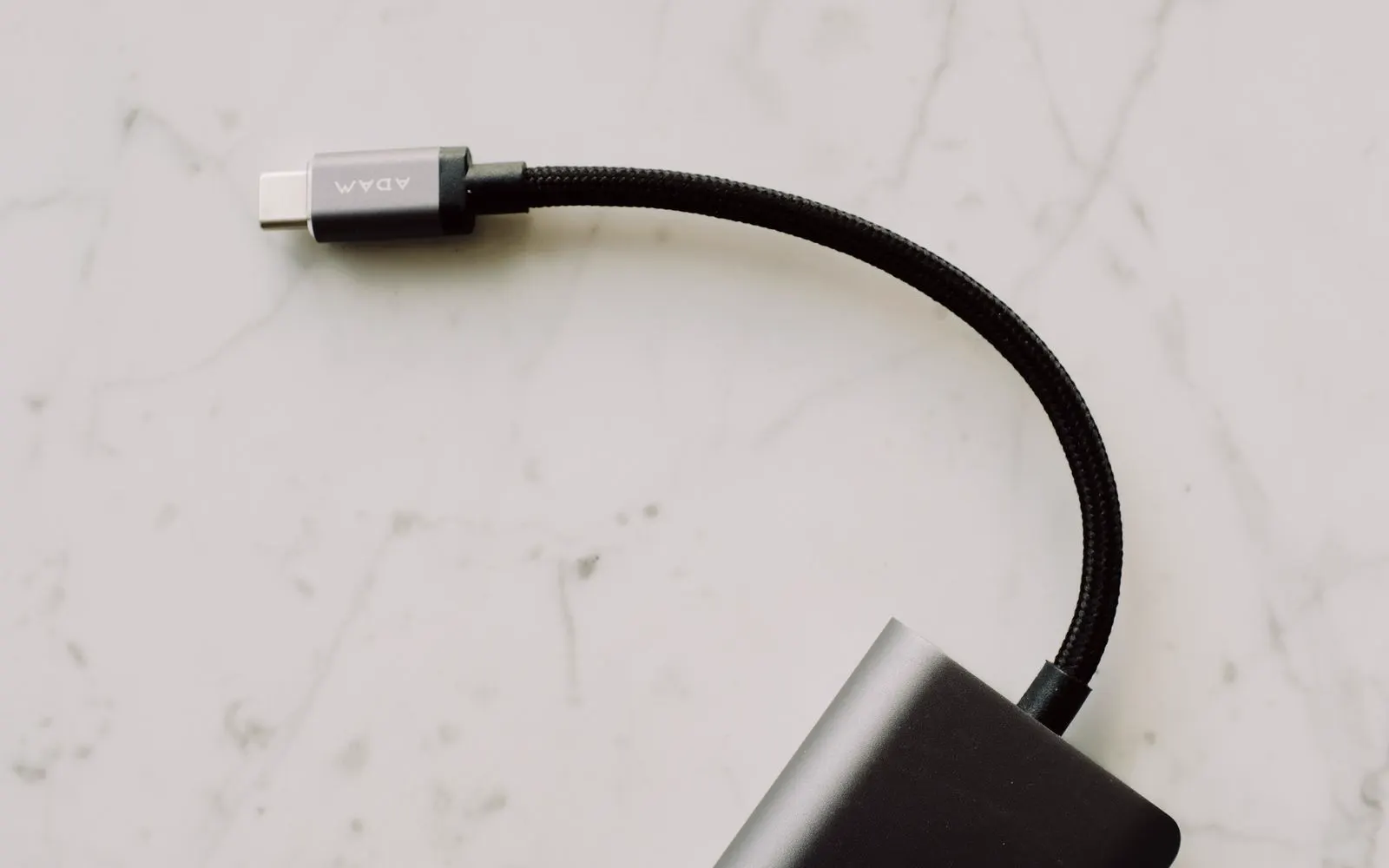 A braided USB-C cable and connector on a light marble surface