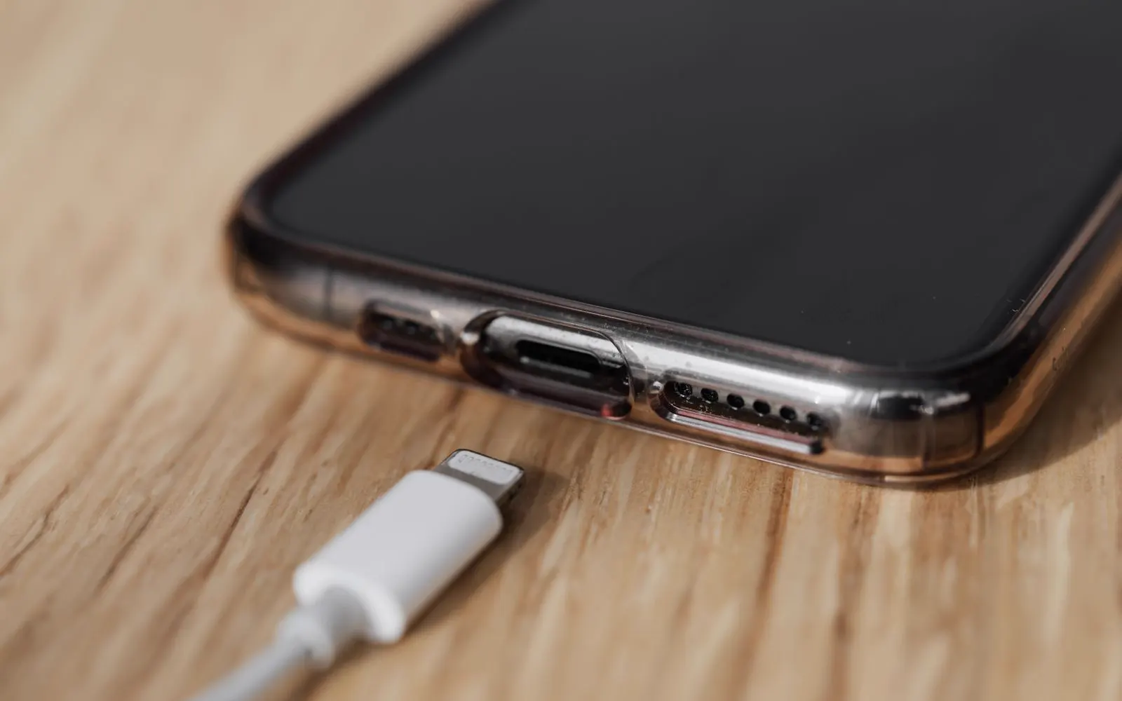 A charging cable held beside the charging port of a smartphone