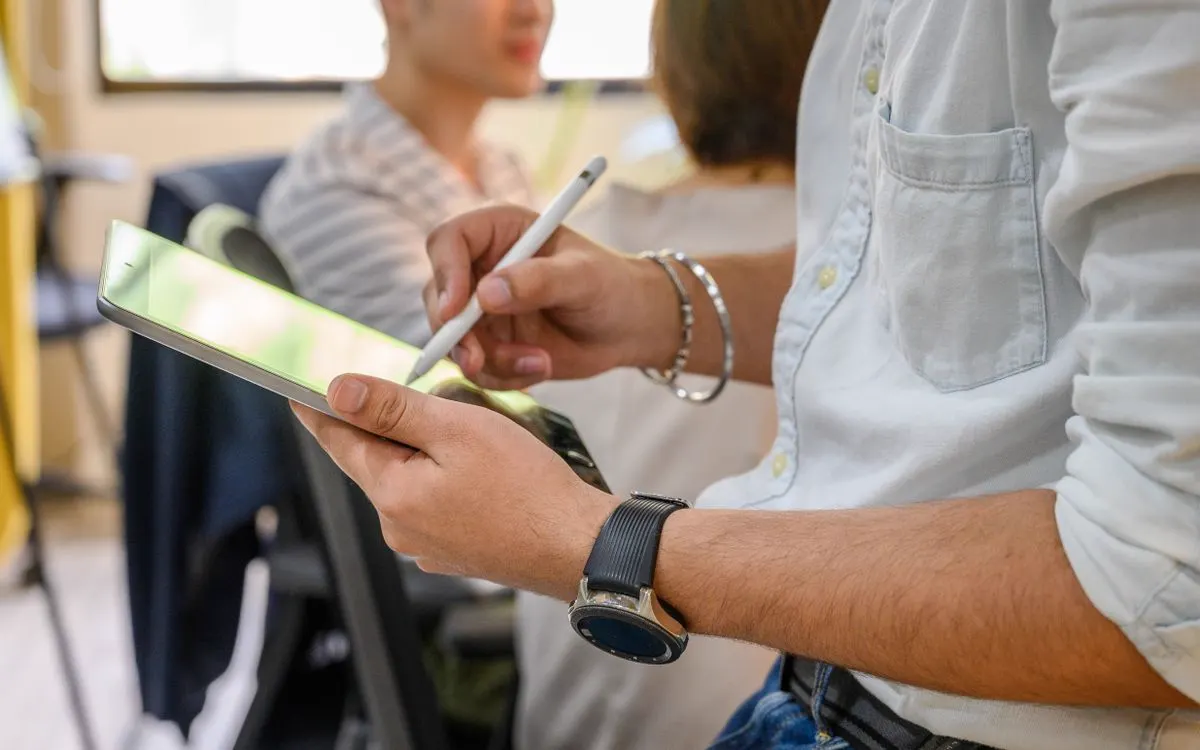 A person checking an iPad screen with an Apple Pencil in hand