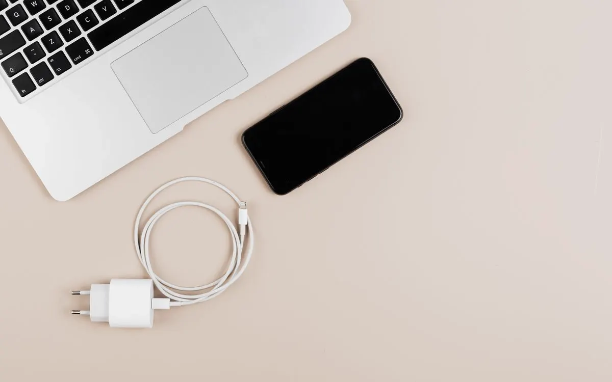 A laptop, smartphone and charger laid out together