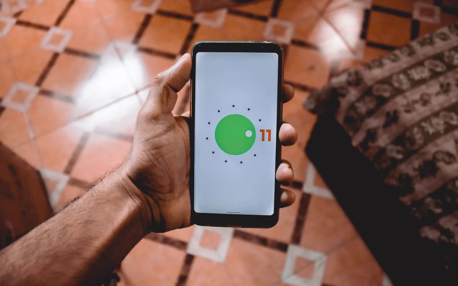 A hand holding an Android phone showing its home screen