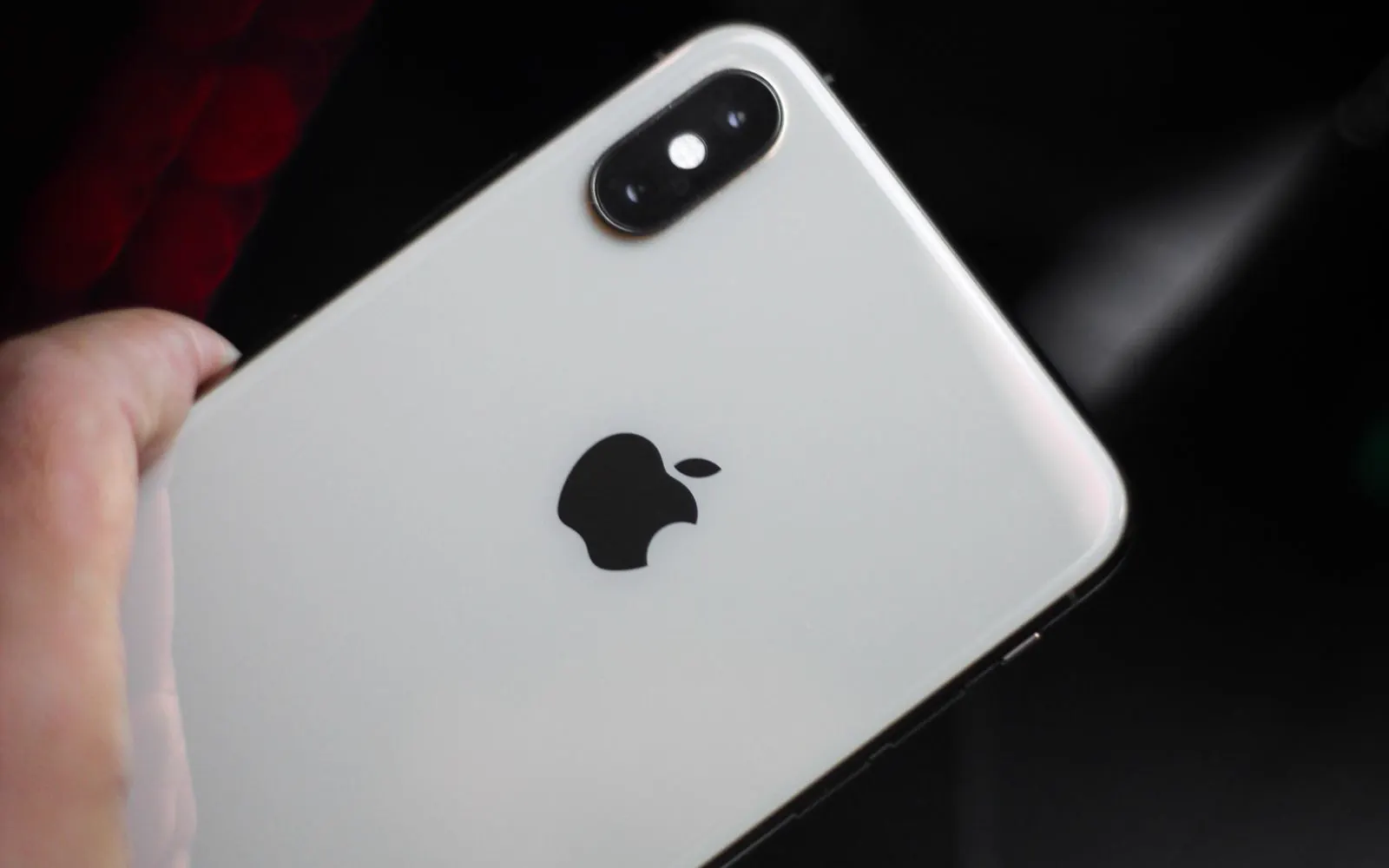 A hand holding a repaired iPhone against a plain background
