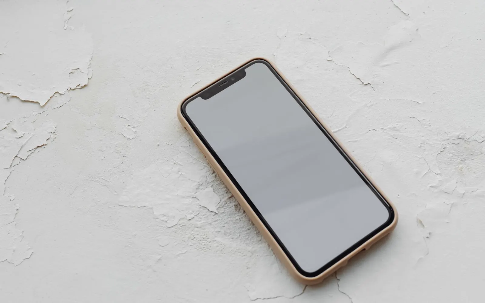 A phone resting face up on a cracked white surface