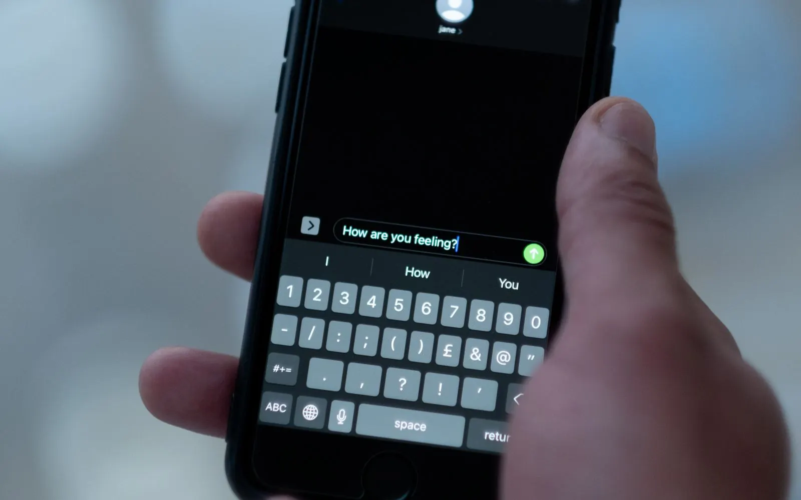 A hand typing a message on a smartphone keyboard