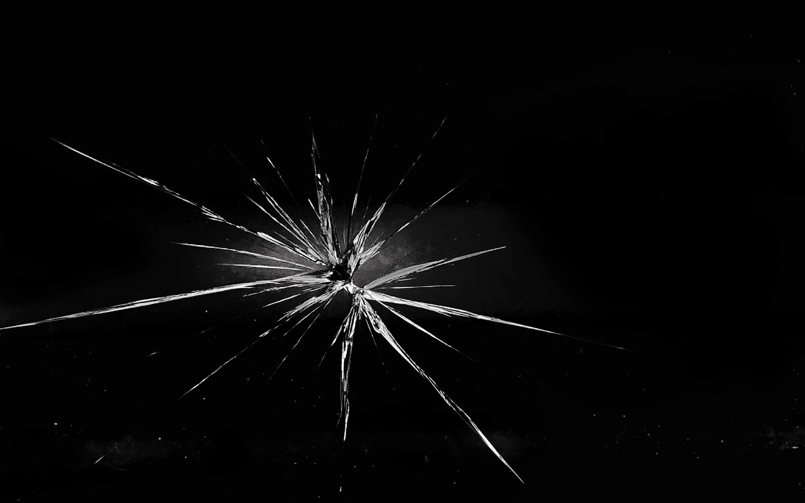 Cracks radiating out from a single point across a sheet of black glass
