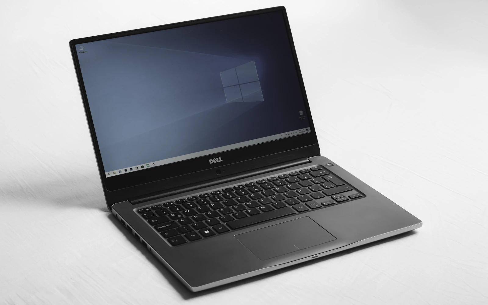 An open Dell laptop on a white surface, its screen showing a blue desktop