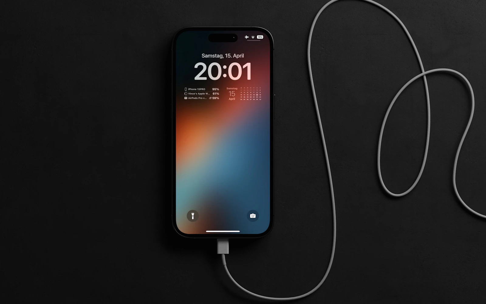 An iPhone with a Dynamic Island plugged into a charging cable, lying on a dark surface